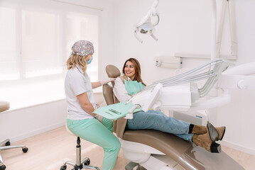 Female dentist preparing mid adult woman patient on chair for dental check up in a modern clinic