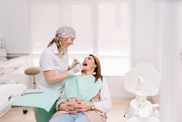 Female dentist examining patient's teeth in modern dental clinic