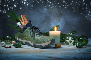 Nikolaus Tag at December 6, meaning Saint Nicholas day, traditional German holiday, sneaker filled with treats, candle and Christmas decoration, dark background, cold toned, copy space