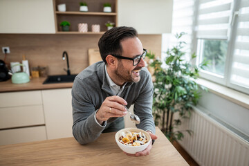 Happy man eating healthy breakfast in kitchen