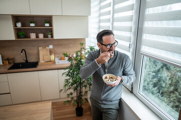 Man eating healthy breakfast cereal in kitchen