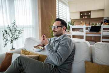 Adult man relaxing on sofa eating healthy snack