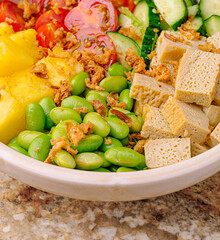 Colorful salad bowl featuring fresh vegetables and tofu on a marble table