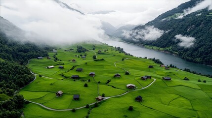 A picturesque aerial view of a remote village with scattered houses and winding paths, set against a backdrop of a tranquil lake and cloud-covered mountains.