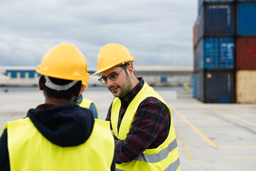 Workers controlling shipping containers at industrial port harbor - Shipment, logistic and industrial concept - Focus on right man helmet
