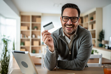 Happy man holding credit card shopping online