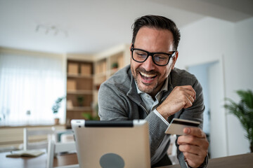 Happy man shopping online with tablet and credit card