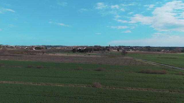 Vue a&eacute;rienne par drone de vastes champs agricoles g&eacute;om&eacute;triques alternant cultures vertes et terre brune avec des traces de machines