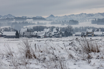 Snowy village with mountain backdrop and winter mist