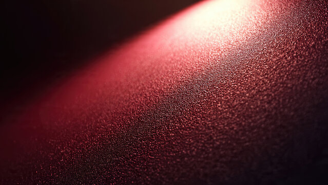 A close-up of a dark, textured surface illuminated by a warm, reddish-orange light, creating a granular and atmospheric glow.