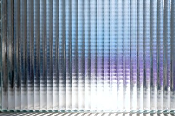 Obraz premium Abstract fluted glass texture with vibrant blue and purple light creating a modern background.