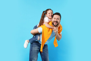 Happy daughter hugging her father on light blue background. Family bonding