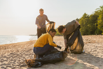 Earth day. Volunteers activists collects garbage cleaning of beach coastal zone. Woman and mans puts plastic trash in garbage bag on ocean shore. Environmental conservation coastal zone cleaning