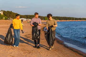 Earth day. Volunteers activists team collects garbage cleaning of beach coastal zone. Woman mans with trash in garbage bag on ocean shore. Environmental conservation coastal zone cleaning