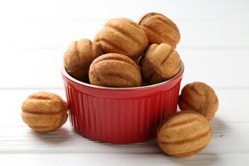 Delicious nut shaped cookies with boiled condensed milk in bowl on white wooden table, closeup