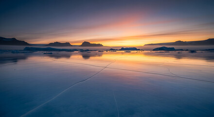 A serene arctic sunset casting a warm glow over a vast frozen sea with distant mountains on the horizon.
