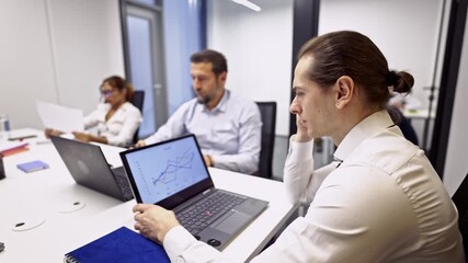 Business coworkers diligently analyze financial data and market trends on laptops during an important office meeting. - Powered by Adobe