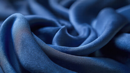 Smooth, elegant indigo blue fabric artfully draped. The soft folds and subtle texture create a luxurious, deep, and calming visual background.