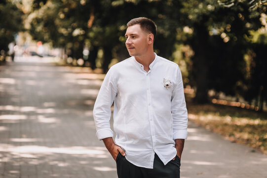 Wedding photography, portrait of happy stylish fashionable young groom in white shirt outdoors in park in nature.