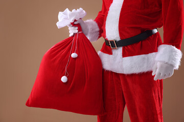 Santa Claus holding sack on beige background, closeup. Merry Christmas and Happy New Year