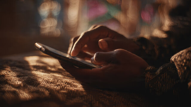 Close-up of hands actively using a smartphone under warm, soft light. Fingers interact with the screen, highlighting modern communication and digital life.