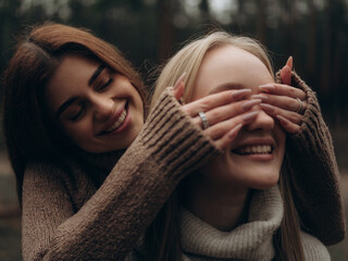 Happy lesbian couple laughing woman playing and covering partners eyes