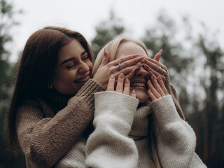 Happy lesbian couple laughing woman playing and covering partners eyes