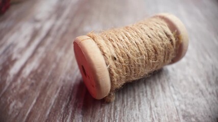 Macro slow motion clip showing twine spool on wooden table as camera moves left, perfect for rustic craft holiday themes
