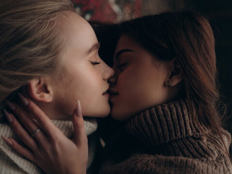 Close-up intimate lesbian couple kissing lying ornate carpet