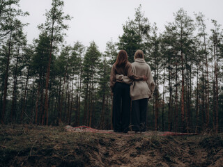Lesbian couple back view embracing against forest landscape
