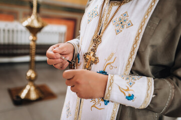 A photograph of a Christian Orthodox priest with a cross on his cassock and anointing oil in his hands for baptism. Concept of religion.