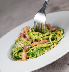 Recipe for linguine pasta with spinach pesto, smoked bacon, and Parmesan cheese. High quality photo