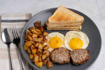 fried eggs served with sausage patties and home fries