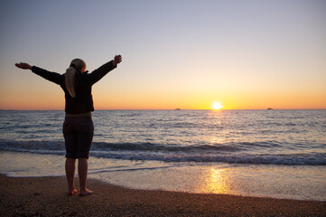 A woman stands on the seashore