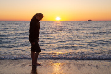 A woman stands on the seashore