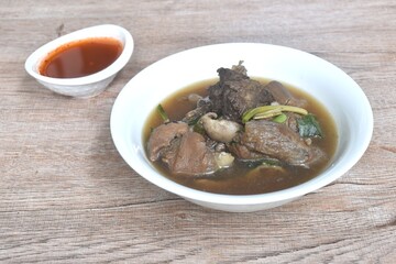 boiled braised beef meat and tendon couple organ in herb brown soup on bowl dipping spicy chili sauce 