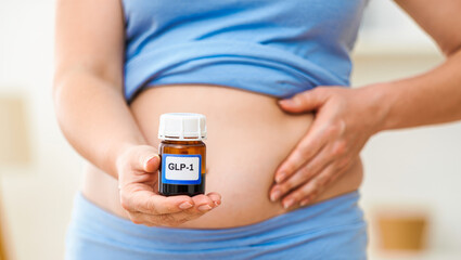 GLP-1 vial held by overweight person on stomach, weight loss, healthcare concept, medical treatment, diabetes management, metabolic health research, pharmaceutical marketing, clinical study imagery