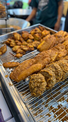 a tray of freshly fried Indonesian banana fritters, or pisang goreng, sits on a wire rack. The golden, crispy coating glistens, with clusters of assorted fritters in the cooling after frying