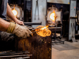 Glassblower craftsman working with hot molten glass in workshop furnace fire manufacturing art handmade creation blowing heat orange glow factory skill traditional master production industry artist