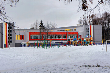 Naklejka premium A playground in front of a building covered in snow