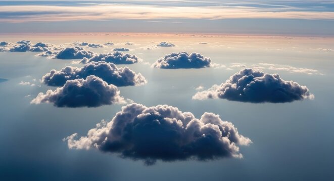 High-angle shot of fluffy cumulus clouds bathed in sunlight over a sea