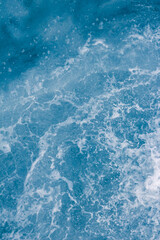 Pale blue sea surface with waves, splash,  foam and bubbles at high tide and surf, abstract background