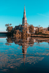 St Alban's Church reflected in the water in late autumn against the blue sky