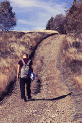 The concept of loneliness and sadness, a single man walking along a road in a field of dry grass
