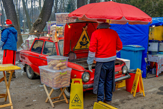 A man in a santa claus outfit standing next to a red truck with a red umbrella
