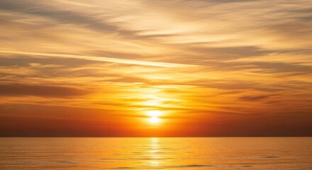 Obraz premium Ocean sunset featuring warm, orange, and golden skies