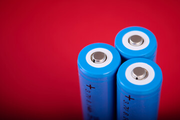 Three blue rechargeable lithium batteries, size 18650, on a red table.