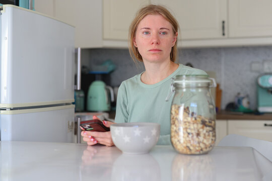Relaxed morning at home, woman enjoying breakfast and scrolling through smartphone