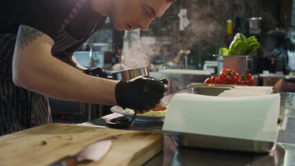 Dynamic close up shot of two chefs passing pans while cooking together in professional restaurant kitchen and plating intricate dishes, copy space