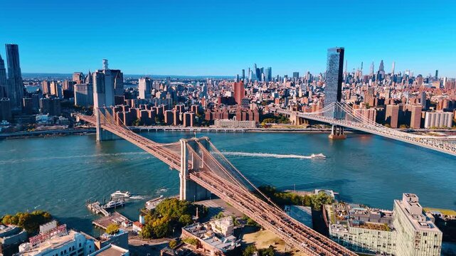 Motorboat moves among the famous bridges of New York, USA. Aerial perspective eon the East River and sunny cityscape.